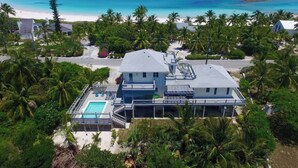 A two-story house with a swimming pool, surrounded by palm trees and a beach view. - Newly Updated Beach House @ Famous French Leave Bch, Htd Pool, Paddle Boards (Governors Harbour)