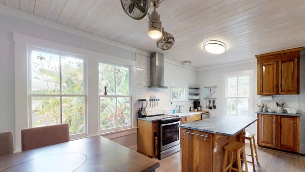 A spacious kitchen with a large island, wooden cabinets, and a central range hood. - 💲1920 Lovingly Renovated💲3 KINGS - 2 Block Stroll to Historic DT- Beach just 3 Miles (St. Augustine)