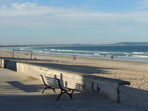 Une plage avec une promenade en béton et un banc.