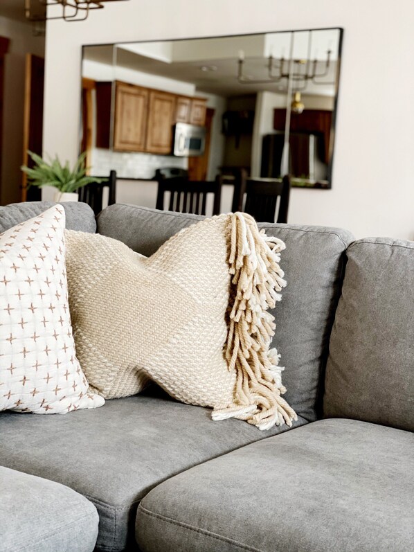 A grey sofa with two decorative pillows and a textured throw blanket.