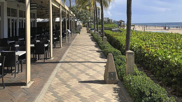 A seaside restaurant with outdoor seating, a paved walkway, and a view of the beach. - Modern & Spacious Luxury Apartment – Steps to the Beach (Deerfield Beach)