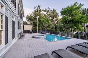 Un área de piscina con jacuzzi, sillas de descanso y una terraza.