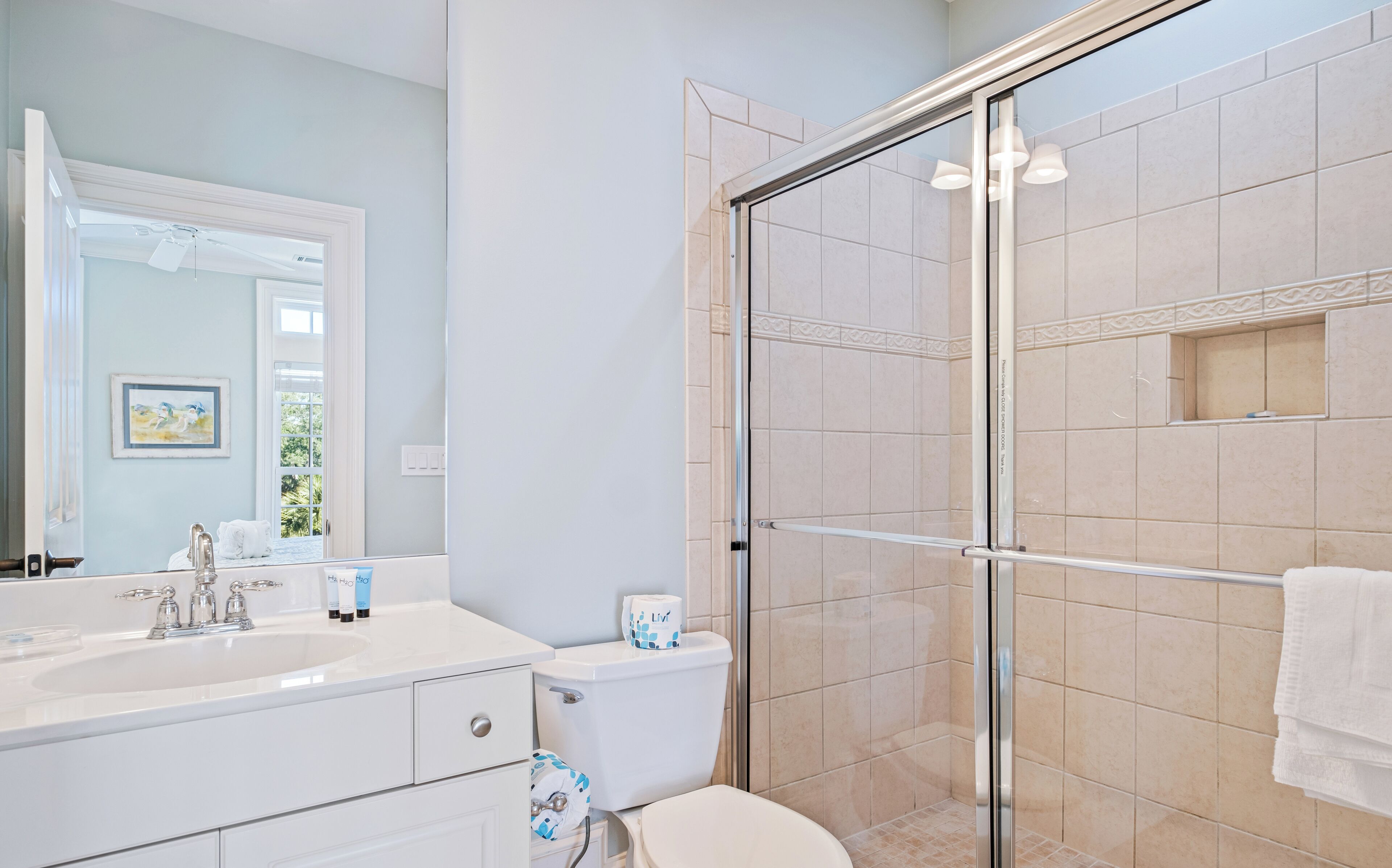 A modern bathroom with a glass shower enclosure, a double sink vanity, and a toilet.