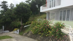 A residential building with a stone retaining wall, a concrete staircase, and a lush garden with flowering plants. - OCEAN VIEW "GATED" AND ACROSS THE WYNDHAM HOTEL!!! (RIO GRANDE RIO MAR)