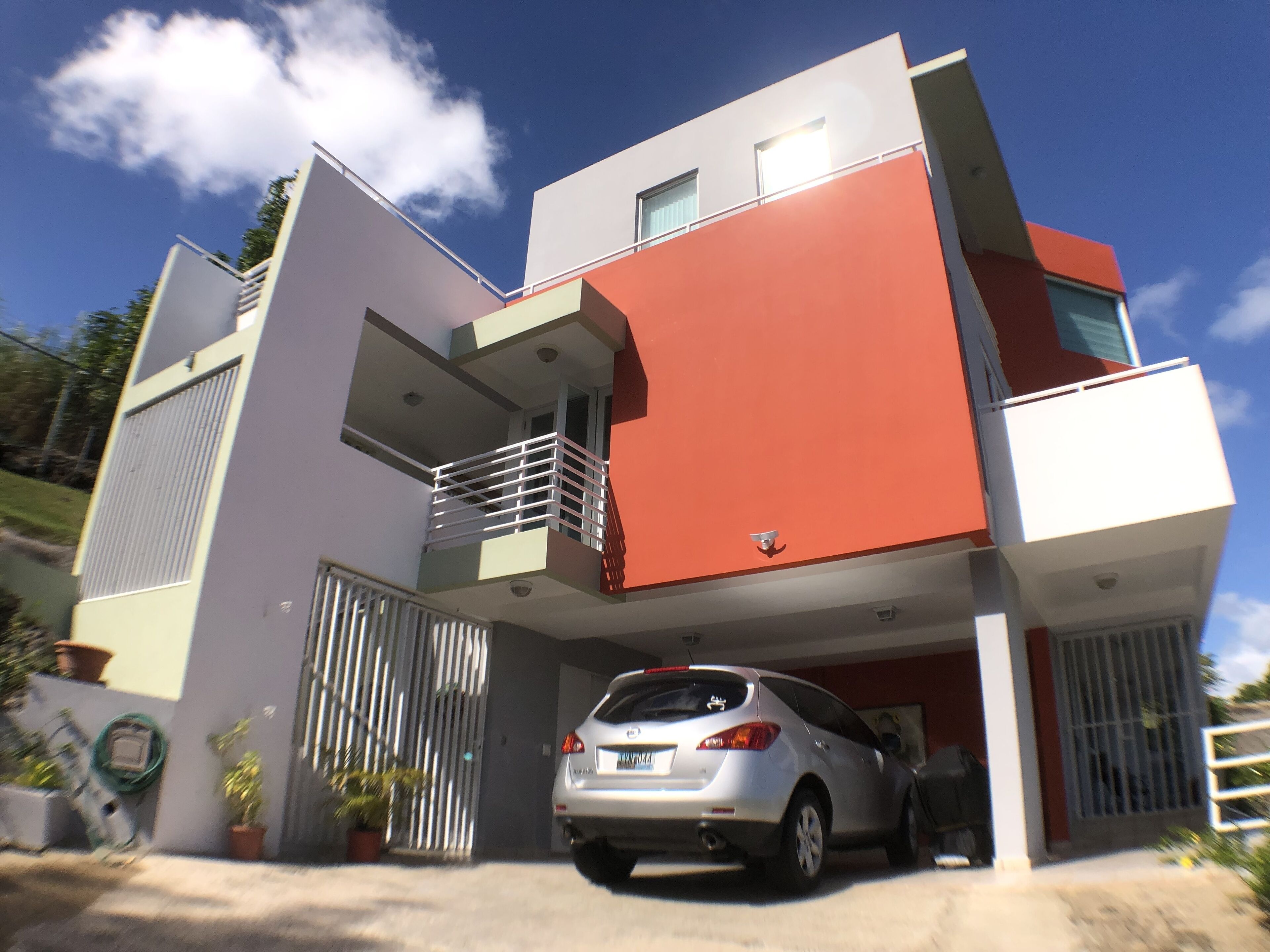 A modern two-story house with a car parked in the driveway.