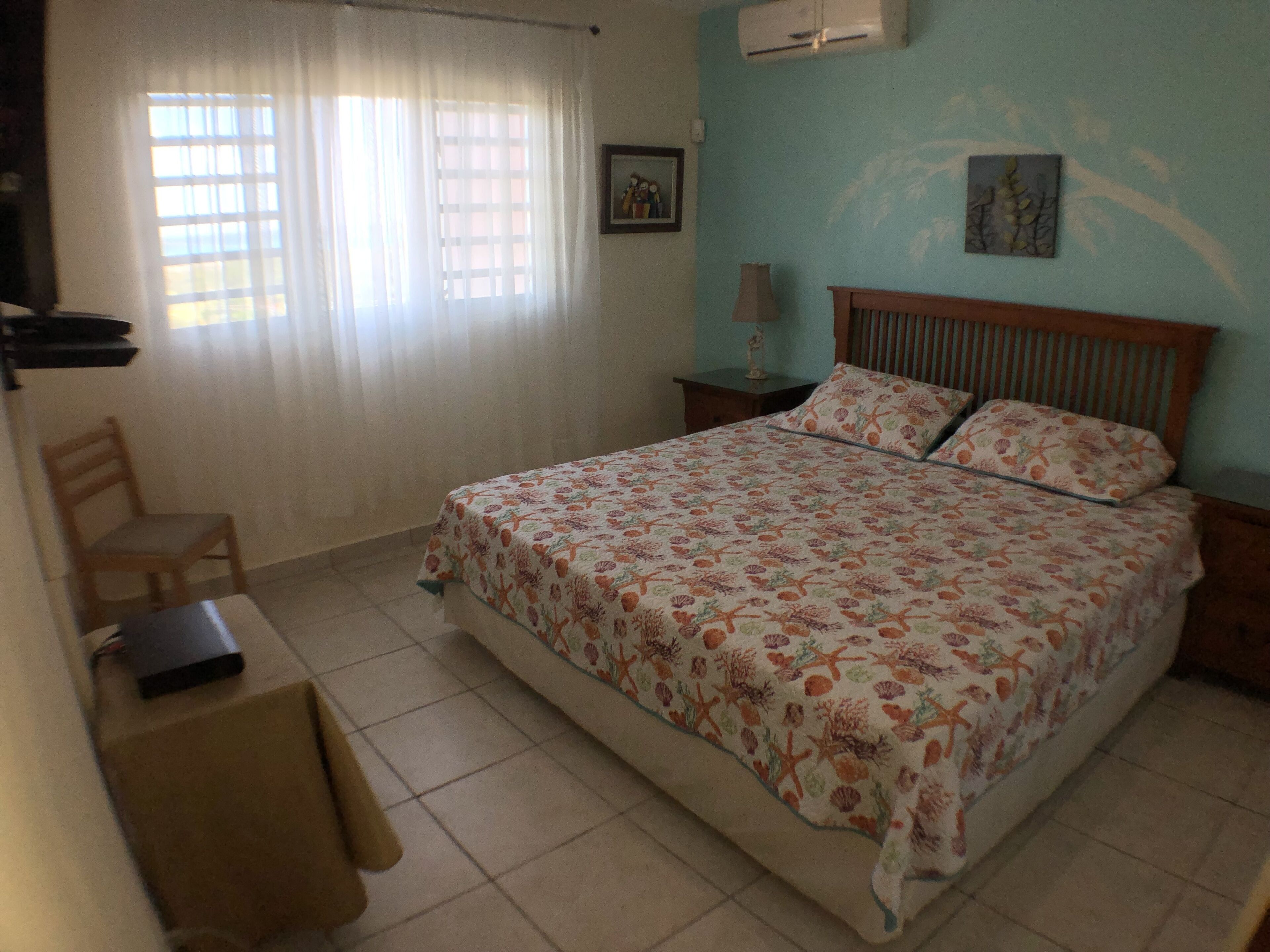 A bedroom with a bed, a chair, a desk, and a nightstand.