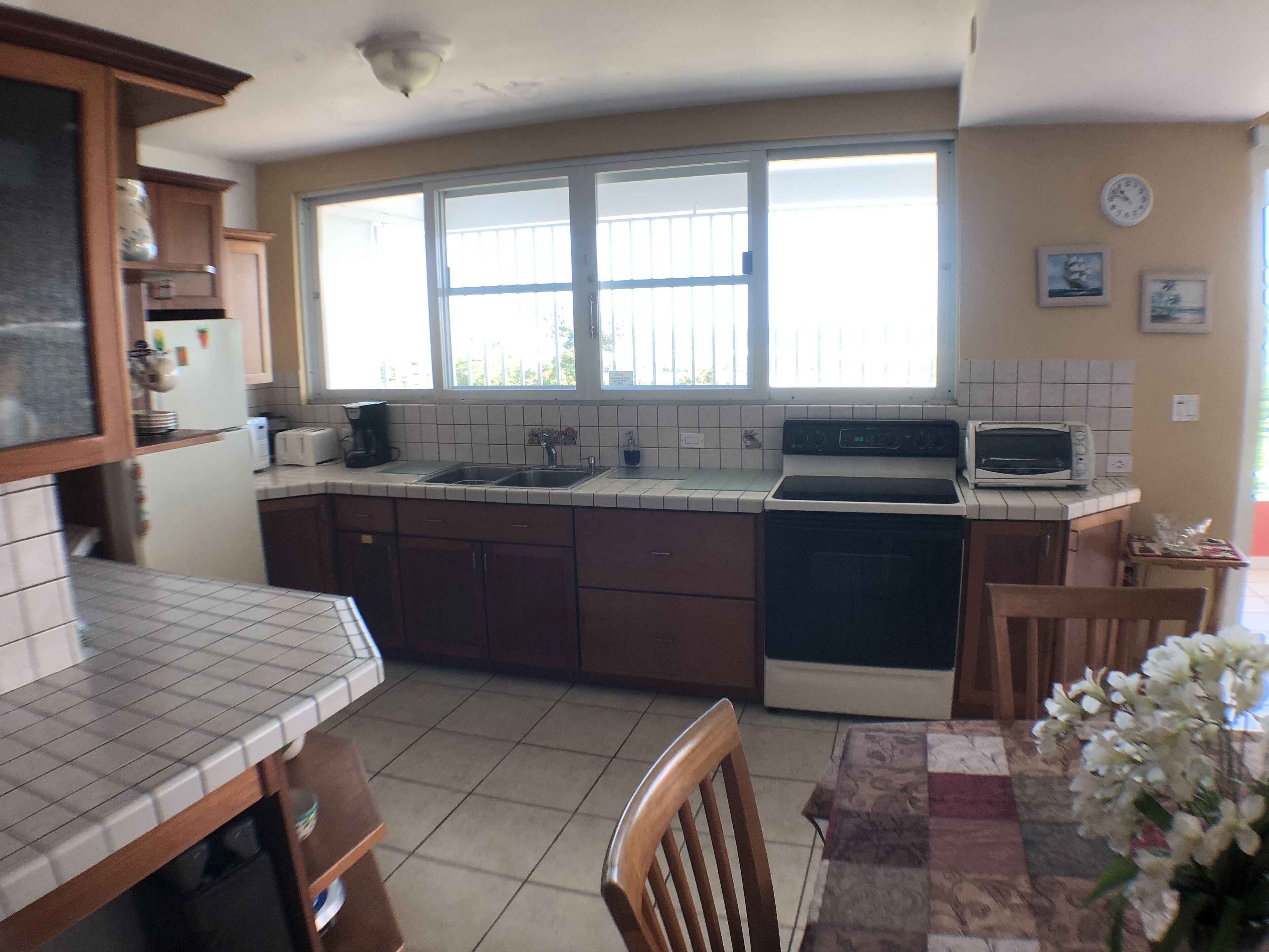 A kitchen with a large window, a microwave, a toaster, and a sink.