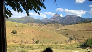 Una persona sentada en una terraza de madera con vistas a un paisaje montañoso.