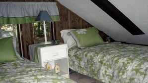 A bedroom with two beds, a nightstand, and a lamp.