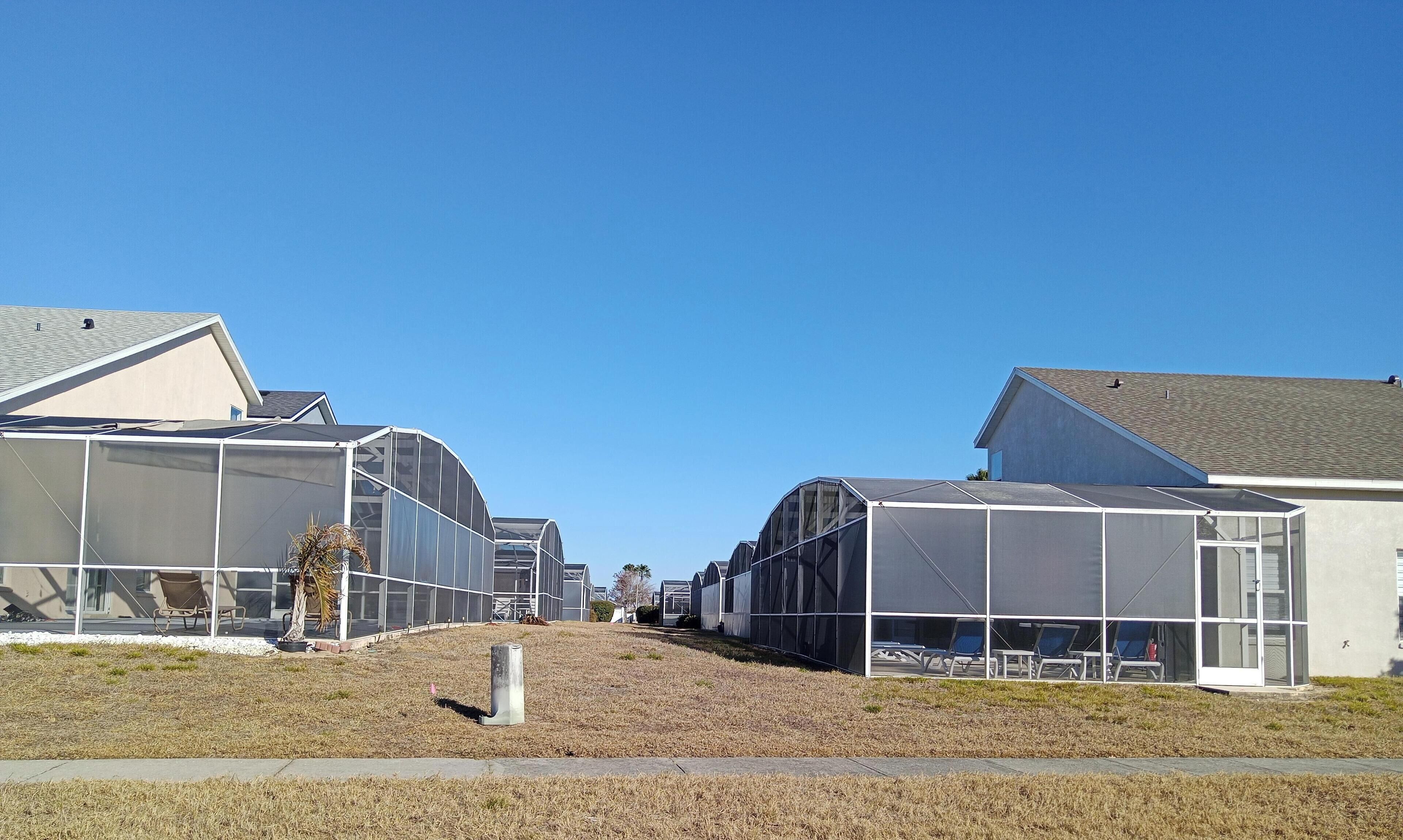 Une rangée de serres modernes, à la structure semi-transparente, avec un ciel dégagé en arrière-plan.