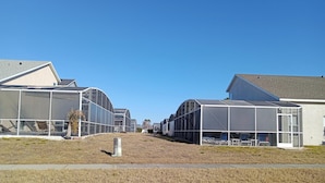 Une rangée de serres modernes, à la structure semi-transparente, avec un ciel dégagé en arrière-plan.