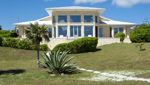 Une grande maison moderne, dotée d’un toit plat, de nombreuses fenêtres et d’une pelouse bien entretenue.
