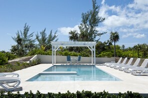 A pool area with a pergola, lounge chairs, and a view of the ocean. - Private Beachfront Estate w/Heated Pool on Pink Sand Beach (Double Bay)