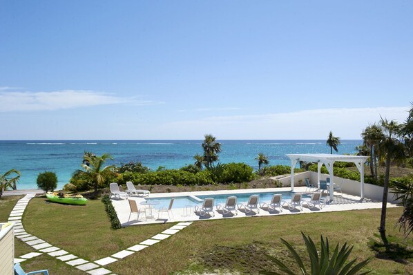 A pool area with lounge chairs and a cabana overlooking the ocean. - Private Beachfront Estate w/Heated Pool on Pink Sand Beach (Double Bay)