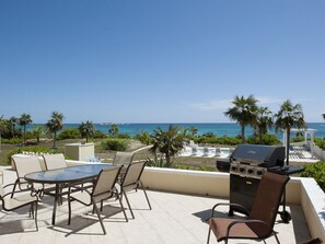 An outdoor patio with a grill, seating area, and a view of the ocean. - Private Beachfront Estate w/Heated Pool on Pink Sand Beach (Double Bay)