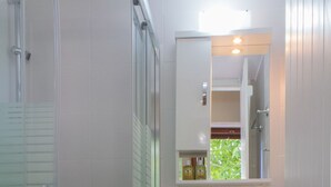 A bathroom with a glass shower enclosure, a white sink with a mirror above it, and a toilet. - 'Perivoli' Stone House (Eresos Lesbos)