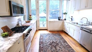 A kitchen with white cabinets, a stainless steel stove, a microwave, and a sink.