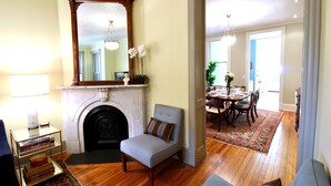 A living room with a fireplace, a dining area with a table and chairs, and a hallway leading to another room.