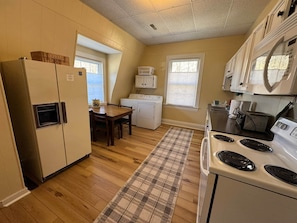 A compact kitchen with a refrigerator, stove, microwave, and a dining area with a table and chairs.