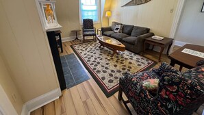 Una sala de estar con sofá, sillón, mesa de centro y una alfombra estampada.