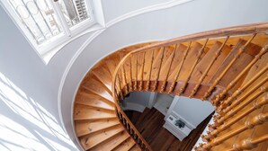 A wooden spiral staircase with a wooden handrail and a window with metal bars at the top. - Acropolis Whitehouse Mansion in Plaka by JJ Hospitality (Athina)