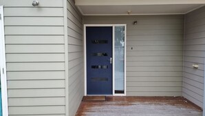 A front door with a dark blue color, a small porch area, and a light gray siding exterior. - One Level at Broadbeach - Inverloch (Inverloch)