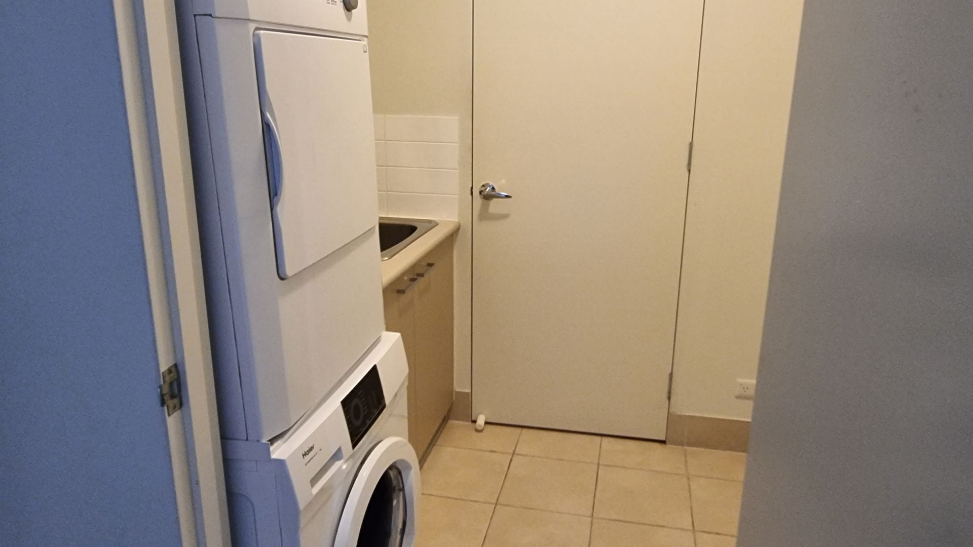 Une petite buanderie équipée d’un lave-linge, d’un sèche-linge et d’un petit évier.