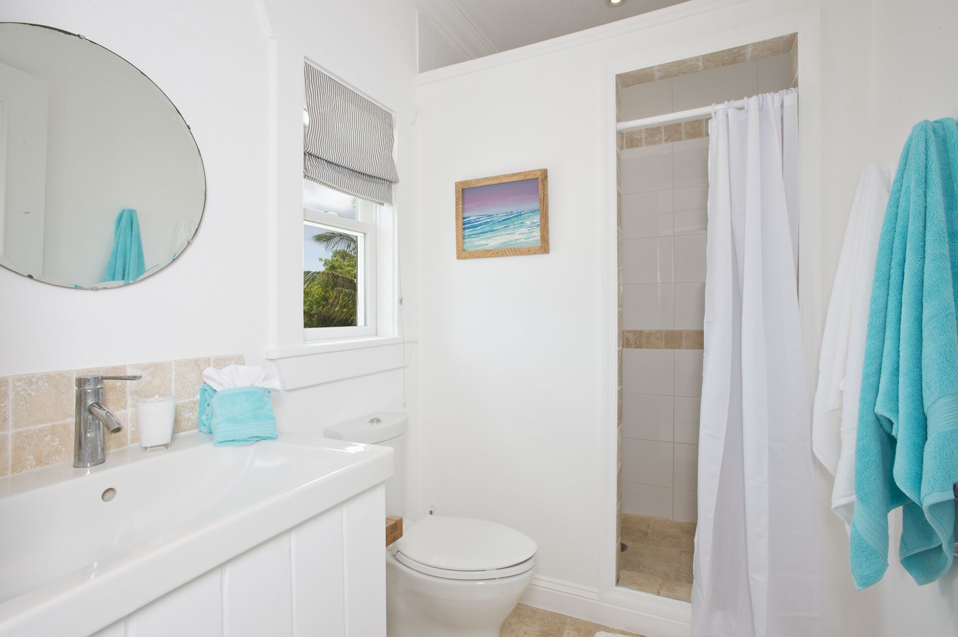 A bathroom with a white sink, toilet, and shower curtain. There is a window with a view of greenery outside.
