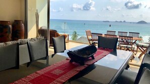 A dining area with a glass table and chairs, a red runner, and a view of the ocean. - Amara Ixtapa, Luxury Oceanfront Condo, 6th Floor (Ixtapa)
