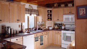 A kitchen with wooden cabinets, a sink, a stove, and a microwave. - Lakefront home with something to enjoy for every season! (Lee)