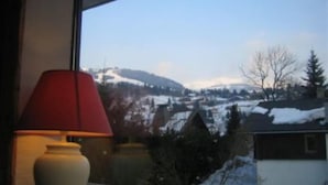 A window with a view of a snowy landscape and a lamp on the windowsill.