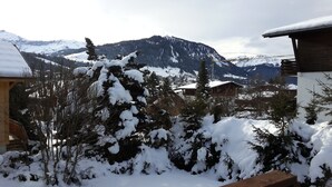 A snowy mountain landscape with a wooden cabin and a view of the mountains.