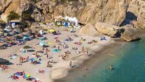 Une plage avec des transats, des parasols et des gens qui se baignent.