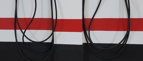 Two wall-mounted electrical outlets with green lights, connected by a white cable.