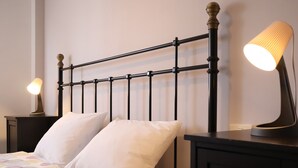 A bed with a patterned bedspread, two bedside lamps, and a black metal headboard.