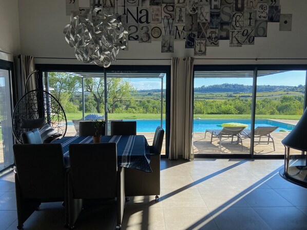 Un comedor con vista a una piscina y al paisaje.