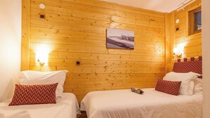 Ein Zimmer mit zwei Betten, Holzwänden, einem Bild an der Wand und zwei Wandleuchten.