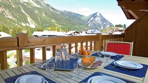 Ein Esstisch mit Bergblick, eine Holzterrasse und ein roter Stuhl.