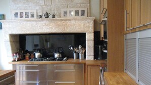 Une cuisine moderne dotée d’une cheminée en pierre, d’appareils électroménagers en acier inoxydable et de meubles de rangement en bois.