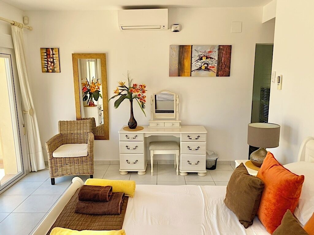 A hotel room with a bed, a desk, a chair, a mirror, and artwork on the walls.
