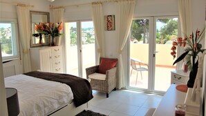 A bedroom with a bed, a chair, a dresser, and a view of the outside. - Beautifully Furnished Family Villa with Spectacular Views and Pool.  (Moriara)
