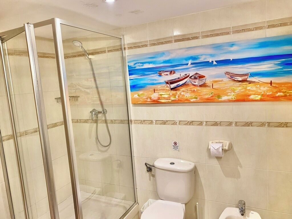 Une salle de bain avec une douche à parois de verre, des toilettes et un lavabo.