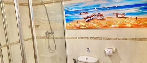 Une salle de bain avec une douche à parois de verre, des toilettes et un lavabo.