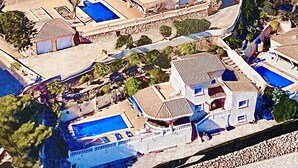 An aerial view of a resort with multiple swimming pools, a large building with a tiled roof, and surrounding greenery. - Beautifully Furnished Family Villa with Spectacular Views and Pool.  (Moriara)