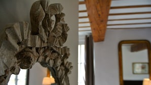 Une pièce avec un plafond en bois, un miroir au mur et une lampe sur une table d’appoint.