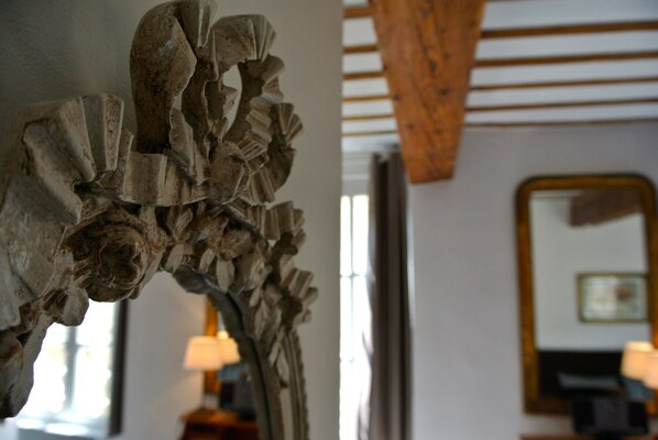 A room with a wooden ceiling, a mirror on the wall, and a lamp on a side table.
