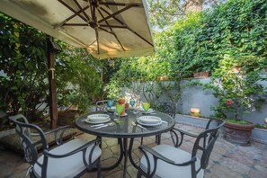 An outdoor patio with a round table, chairs, and an umbrella. - 23Baci, cozy central house with terrace (Capri)