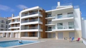 Un moderno edificio residencial de varios pisos con balcones, piscina y zonas de estar al aire libre.