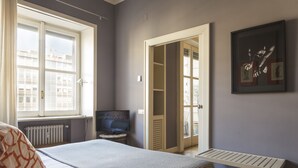 A bedroom with a bed, a television, a window, a door, and a framed picture on the wall. - Milano Charming apartment, a unique home: central area, 2BDR, 2BTH, 4 Guests (Milano)