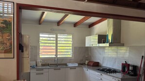 A kitchen with white cabinets, a stove, and a window with blinds. - Villa nanou, quiet villa top with small sea view (BOUILLANTE)